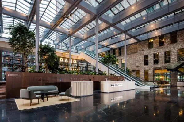 Moderne, lichtovergoten entreehal van het World Trade Center aan de Prinses Beatrixlaan in Den Haag met receptiebalie, zitgedeelte en roltrappen.